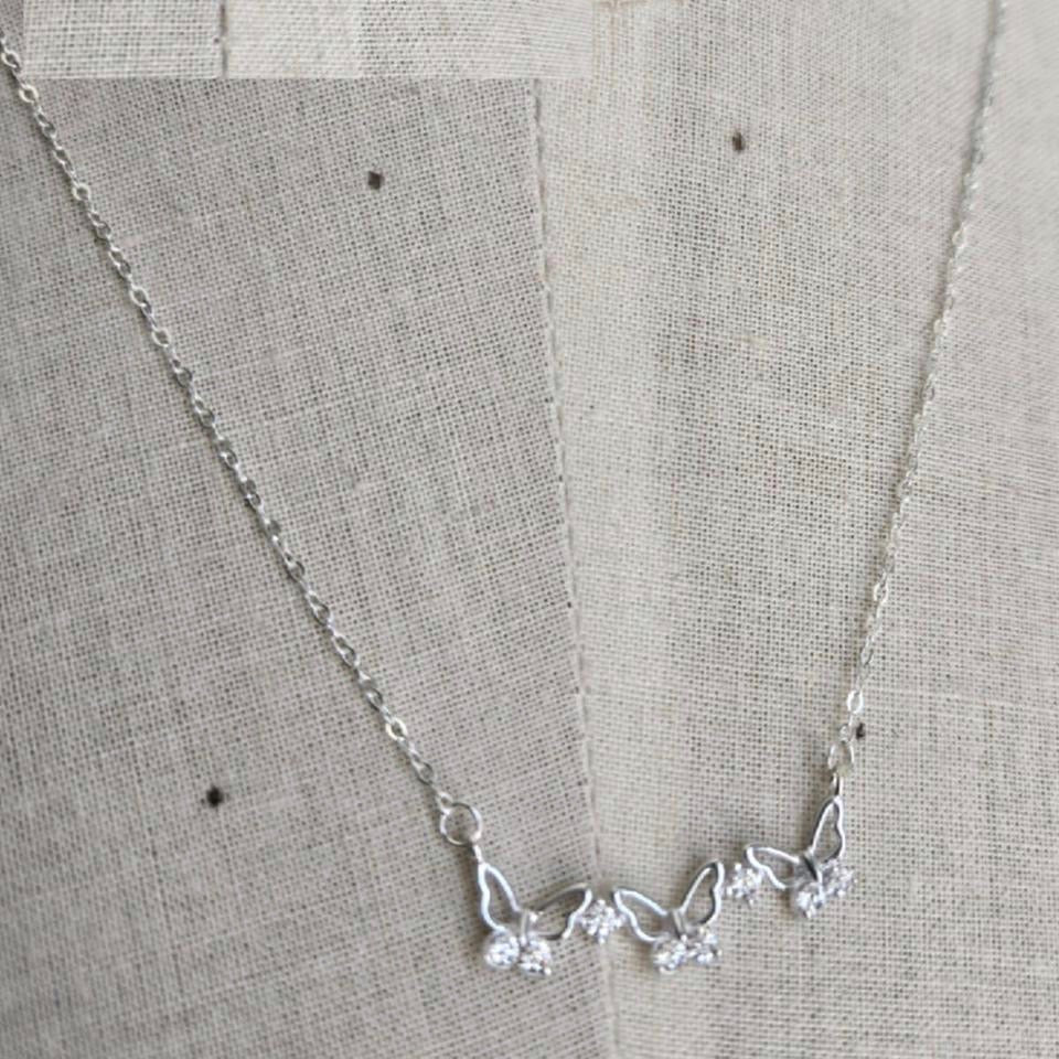 Silver necklace with floral design on a gray fabric background