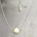 A sterling silver necklace with a chain design and a central freshwater pearl.