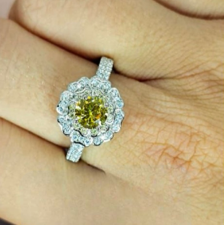 A sterling silver ring with a central cubic zirconia stone in a vibrant yellow hue, surrounded by smaller yellow stones set in a classic six-prong setting.