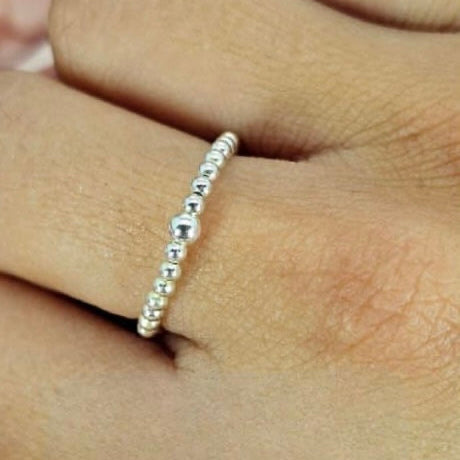 A sterling silver ring with tiny ball details on the band, worn on a person's finger.