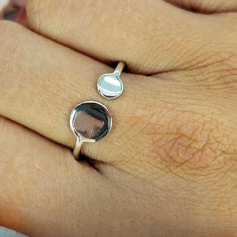 A sterling silver ring with a double circle design, open size, worn on a person's finger.