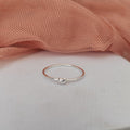 Silver ring with a small ball on a light pink fabric background