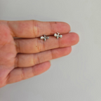 A pair of sterling silver bling butterfly studs with cubic zirconia wings held in a person's hand.
