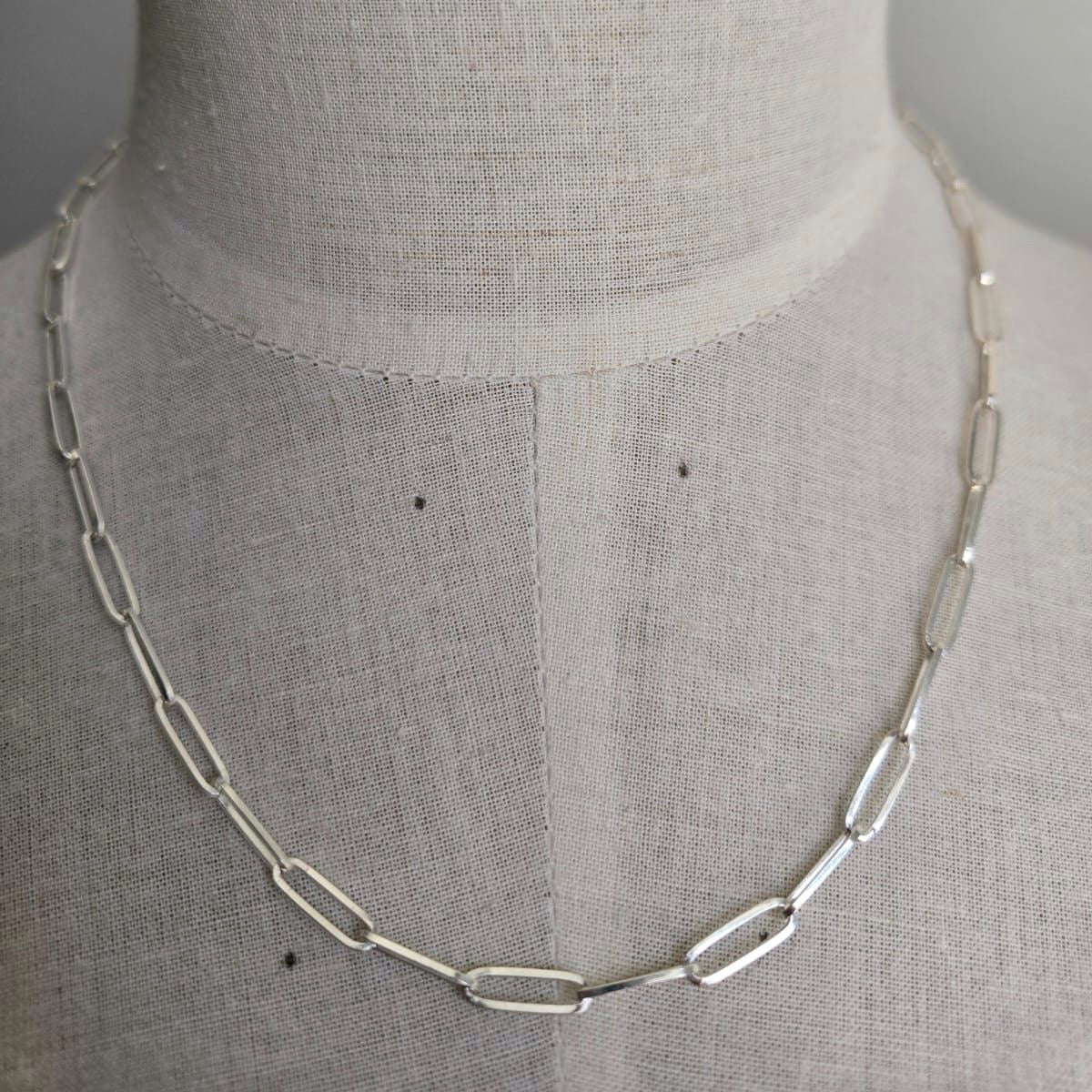 Silver chain necklace on a mannequin with a plain background