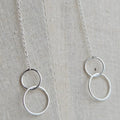 Silver necklace with interlocking rings on a textured fabric background