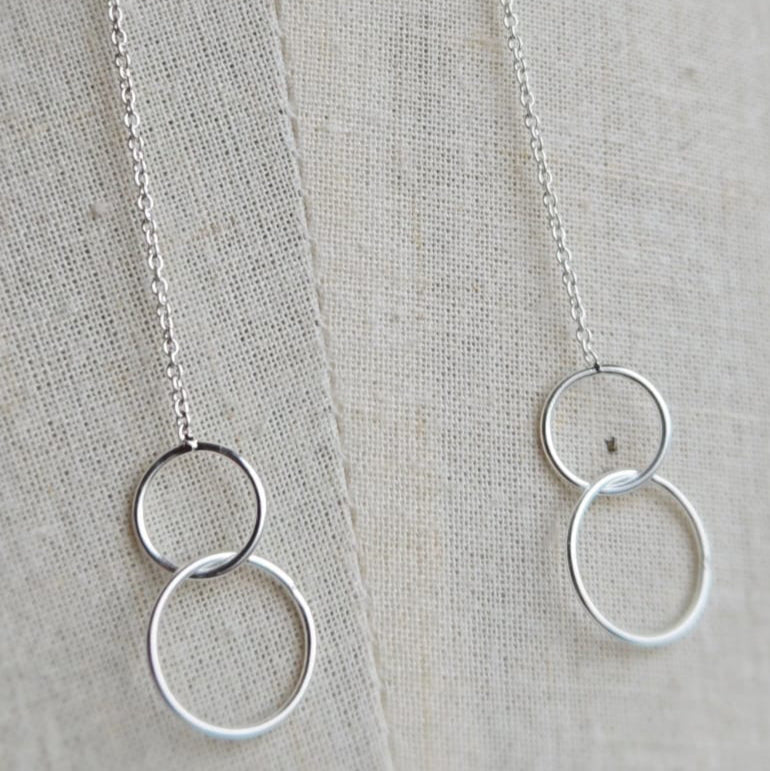 Silver necklace with interlocking rings on a textured fabric background