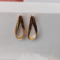 Gold earrings on a light gray surface