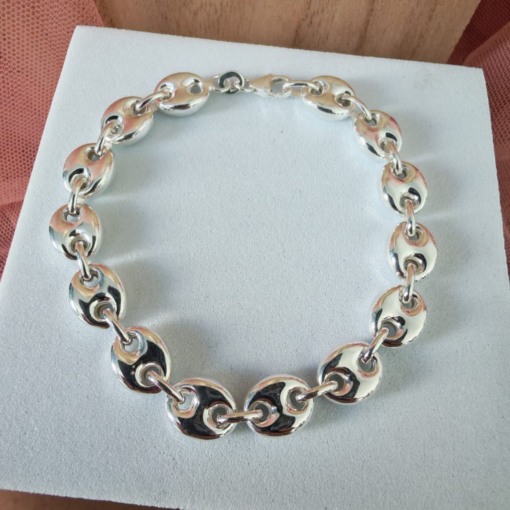 Silver chain bracelet on a white card with a wooden surface in the background