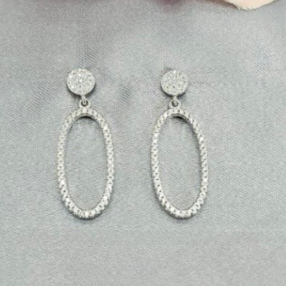 Silver hoop earrings on a gray surface with a pink flower in the background