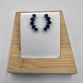 A pair of blue stone earrings crafted from sterling silver, displayed on a white mount and wooden base.