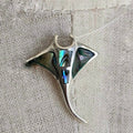 Silver pendant with abalone shell inlay on a textured fabric background