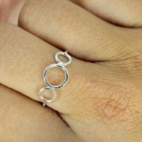 A sterling silver triple circle ring worn on a person's finger, showing the ring's design clearly.