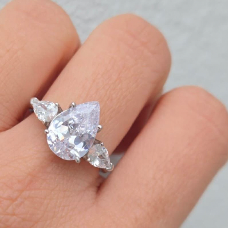 Diamond ring on a finger with a plain background