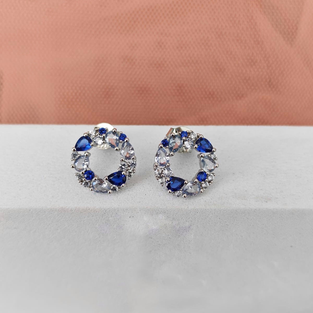 Pair of earrings with blue and clear gemstones on a white surface.