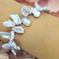 A bracelet featuring uneven freshwater pearls in pink and grey hues, strung together on an elastic band.