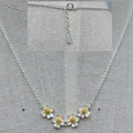 Silver necklace with floral pendants on a gray fabric background