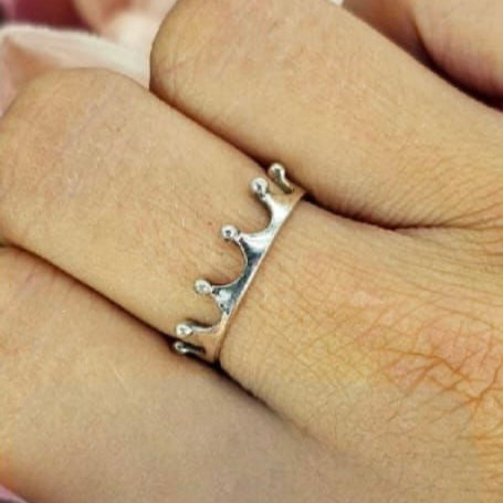 A sterling silver crown ring on a person's finger, showing the detailed design of the crown.