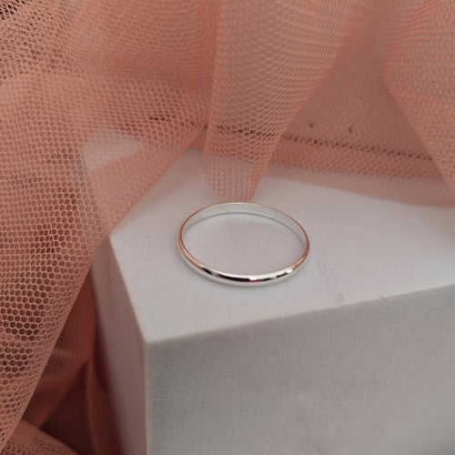 Silver ring on a white box with pink fabric in the background