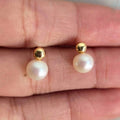 Gold earrings with pearl drops on a hand
