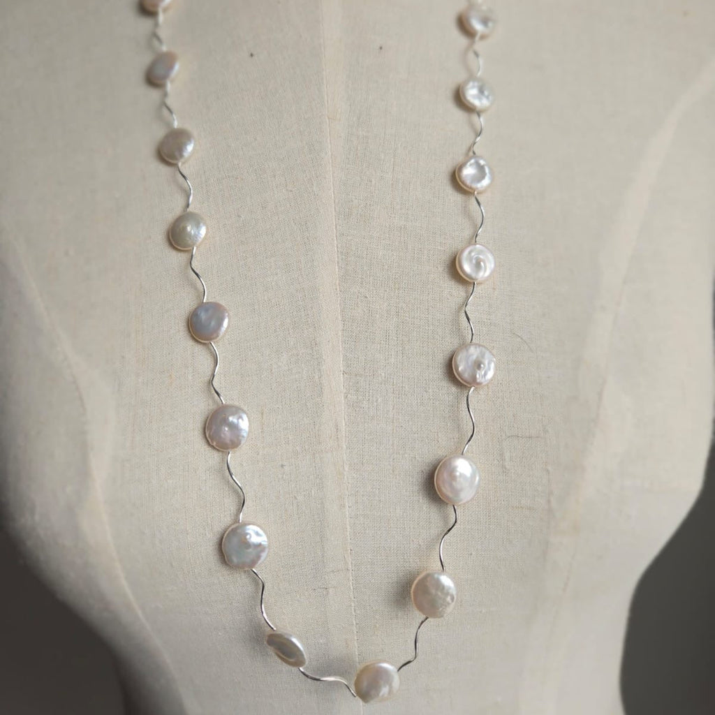 Pearl necklace on a mannequin with a plain background