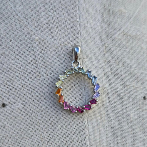 Multicolored gemstone pendant on a textured fabric background