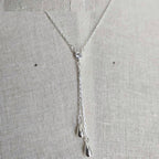 Silver necklace with a heart pendant on a light gray background