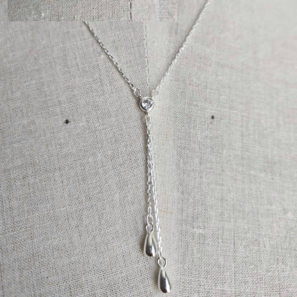 Silver necklace with a heart pendant on a light gray background