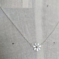Silver necklace with a flower pendant on a gray fabric background