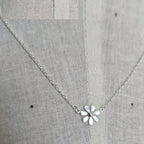 Silver necklace with a flower pendant on a gray fabric background
