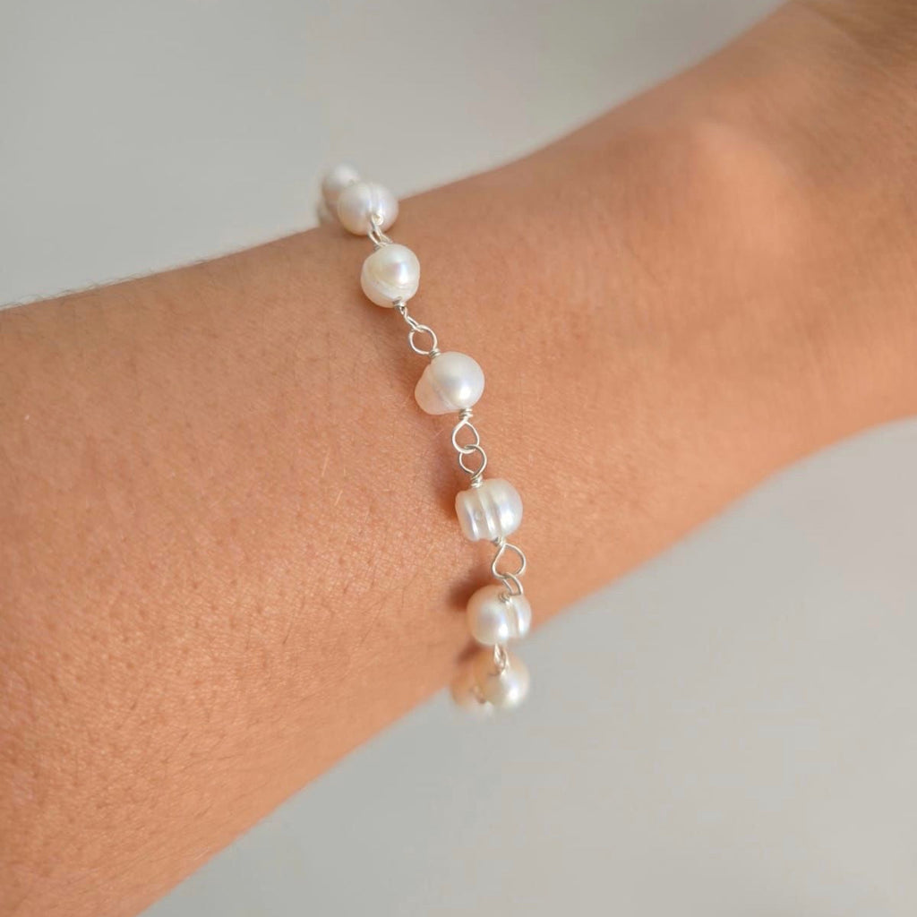 Pearl bracelet on a wrist against a neutral background
