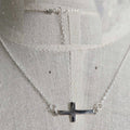 Silver necklace with a cross pendant on a light gray background