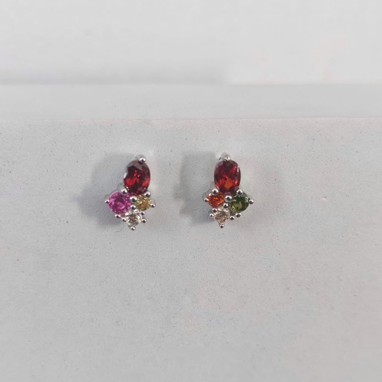 Pair of earrings with multicolored gemstones on a light gray background
