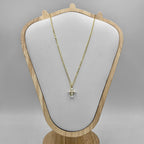 An 18c gold plated necklace with a sterling silver chain and a cross charm made of freshwater pearls, displayed on a wooden mannequin.
