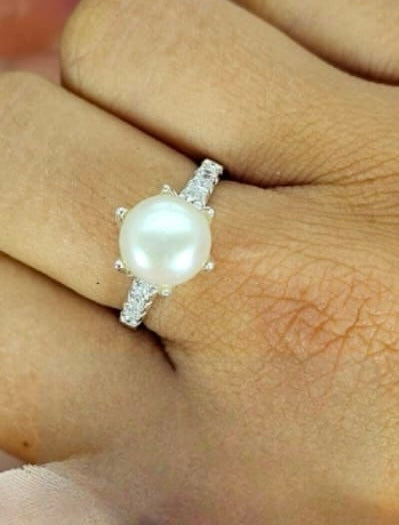 Sterling silver ring with clasp detail round a freshwater pearl