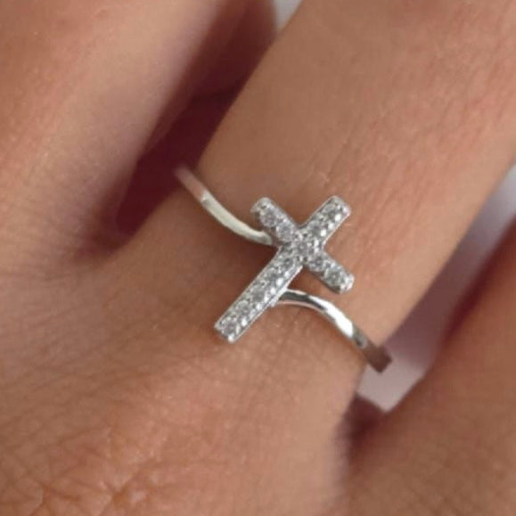 Silver cross-shaped ring on a finger