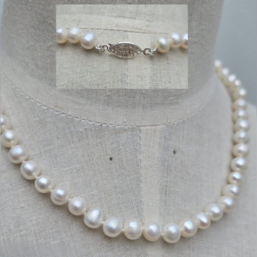 Pearl necklace on a mannequin with close-up of clasp on a light fabric background