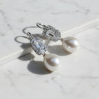 Pearl earrings with green gemstones on a gray background