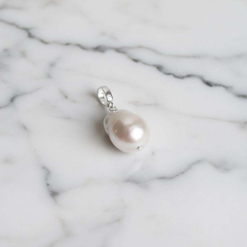 Pearl pendant on a silver chain against a textured fabric background