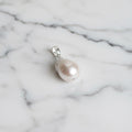 Pearl pendant on a silver chain against a textured fabric background