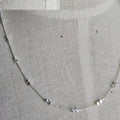 Silver chain necklace on a textured gray fabric background
