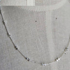 Silver chain necklace on a textured gray fabric background