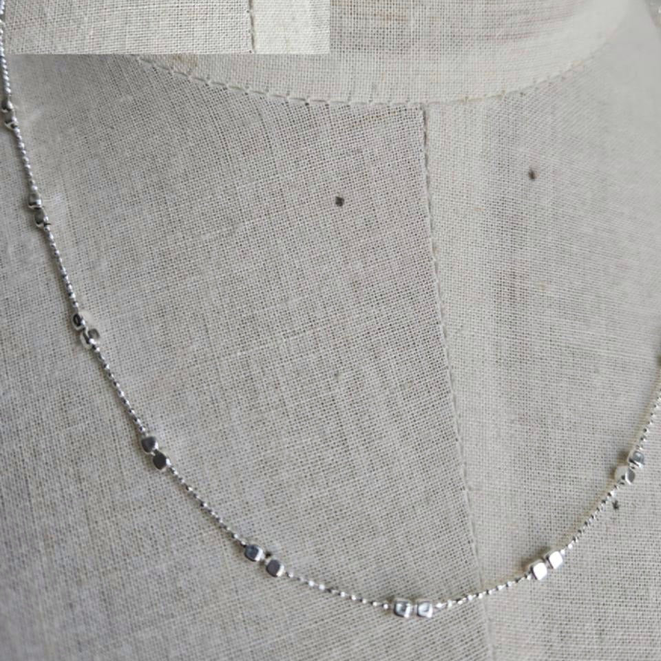 Silver chain necklace on a textured gray fabric background