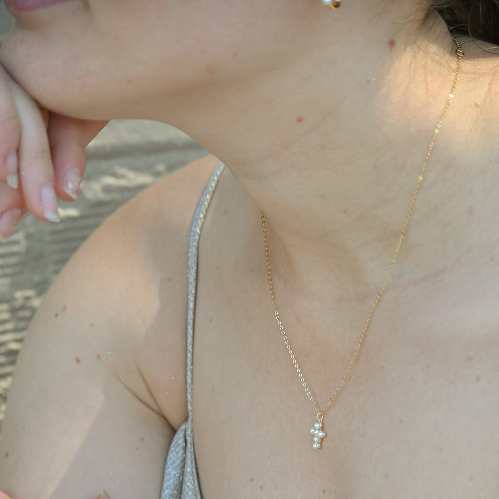 Close-up of a person wearing a delicate gold necklace with a small pendant.