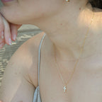 Close-up of a person wearing a delicate gold necklace with a small pendant.