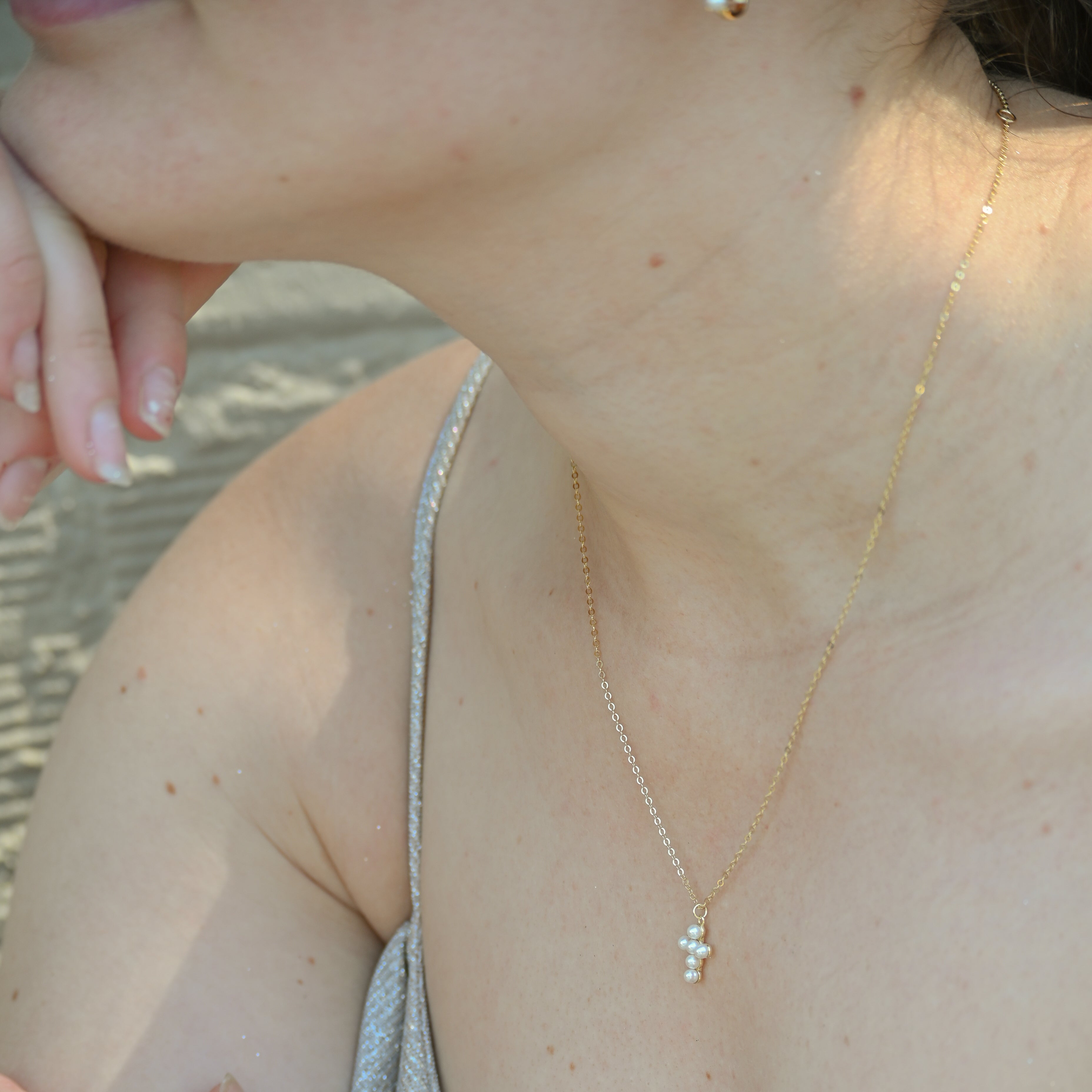 Close-up of a person wearing a delicate gold necklace with a small pendant.