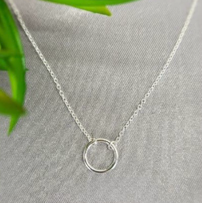 A sterling silver necklace with a large circle detail displayed on a mannequin.