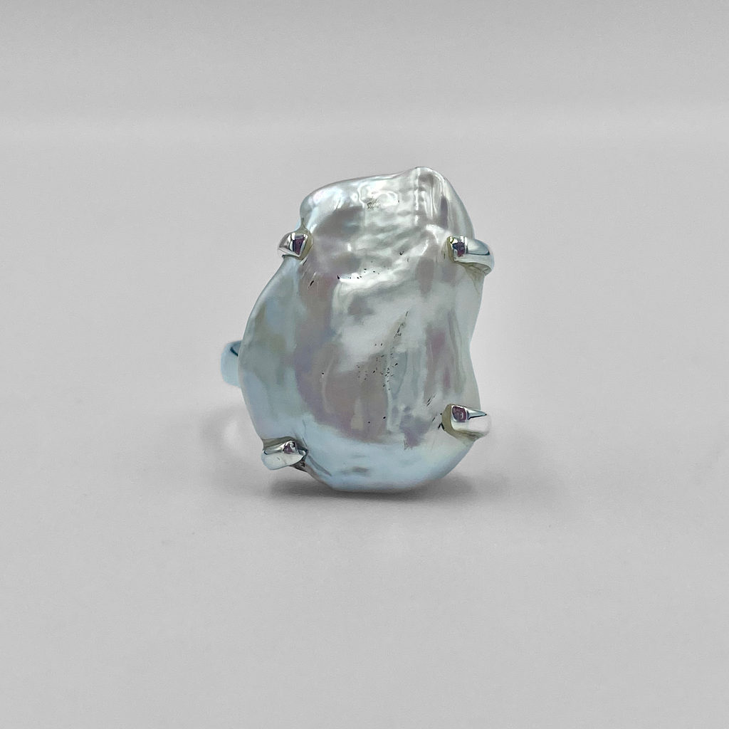 A sterling silver ring featuring a baroque pearl with metallic accents.