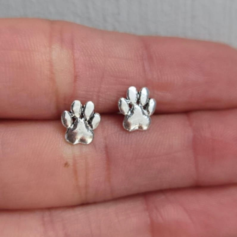 Silver paw print earrings on a person's hand