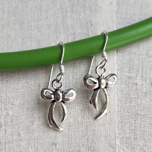 Silver bow-shaped earrings on a green stick against a gray background