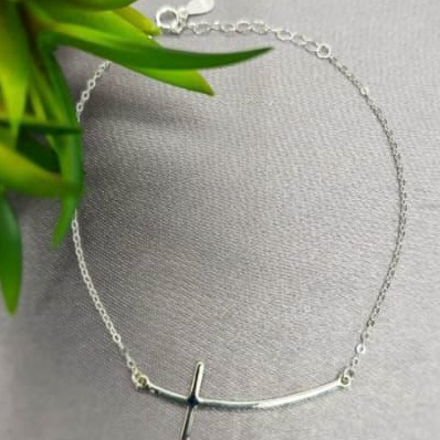 A sterling silver bracelet with a shaped cross design, displayed on a neutral background.